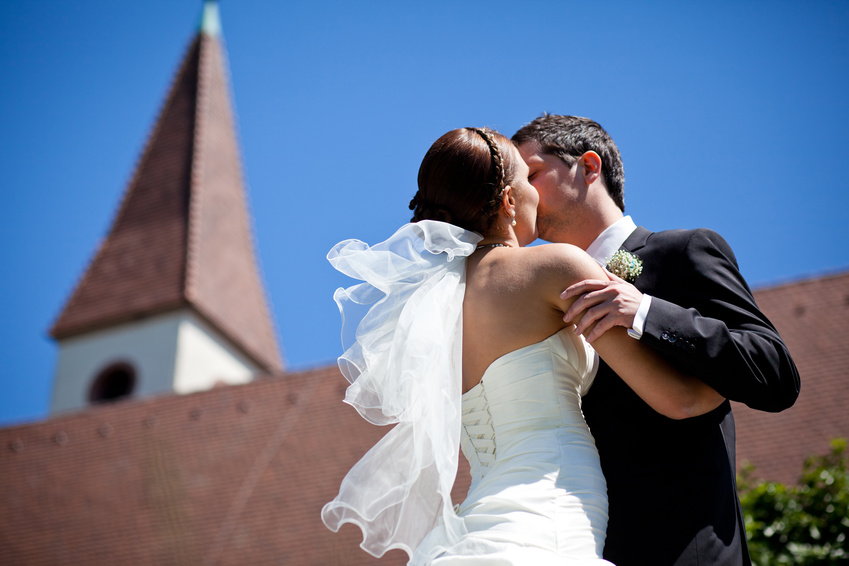 Trauung - Brautpaar küsst sich vor einer Kirche